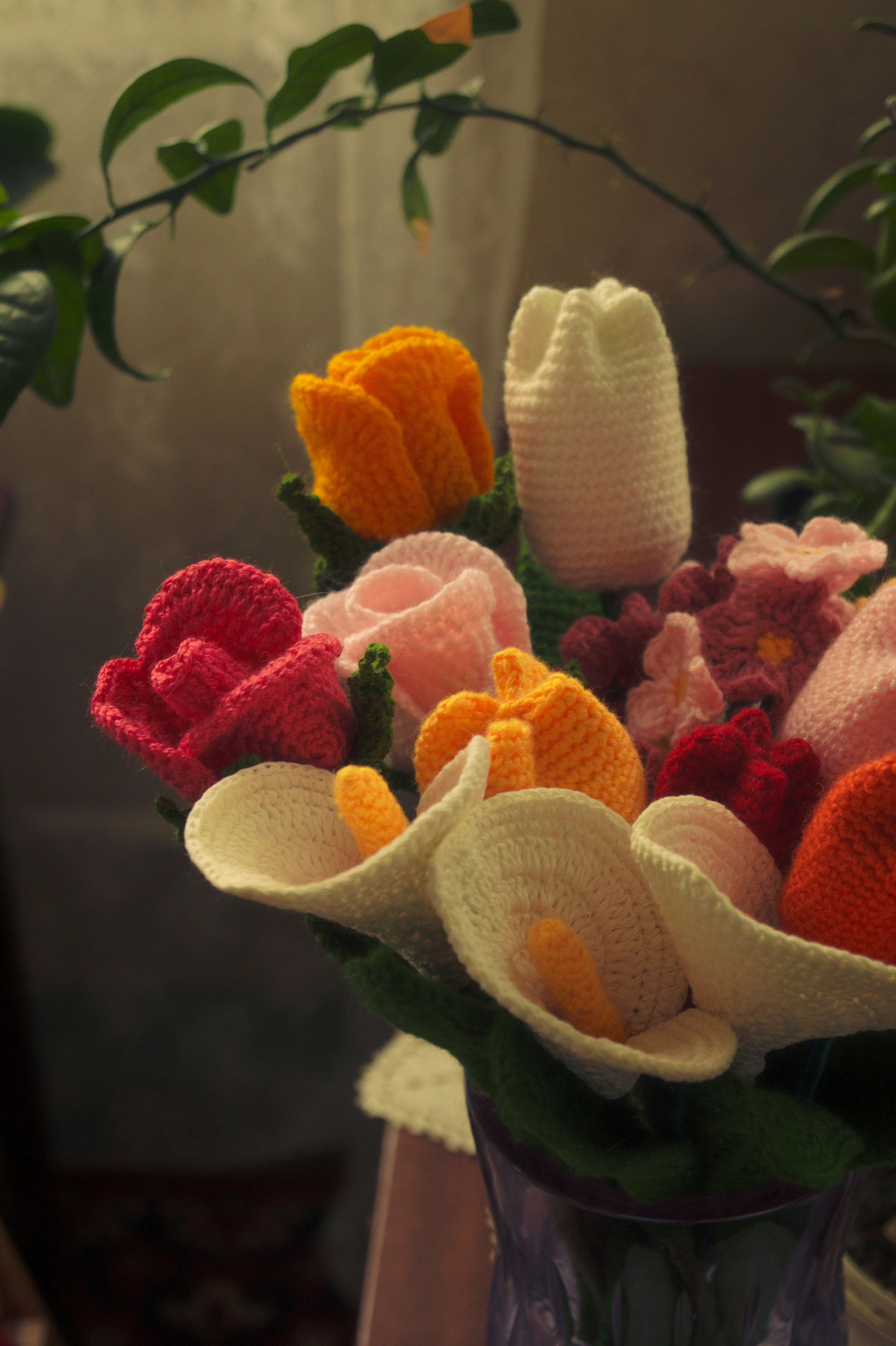 Hands arranging handmade crochet flower stems into a bouquet