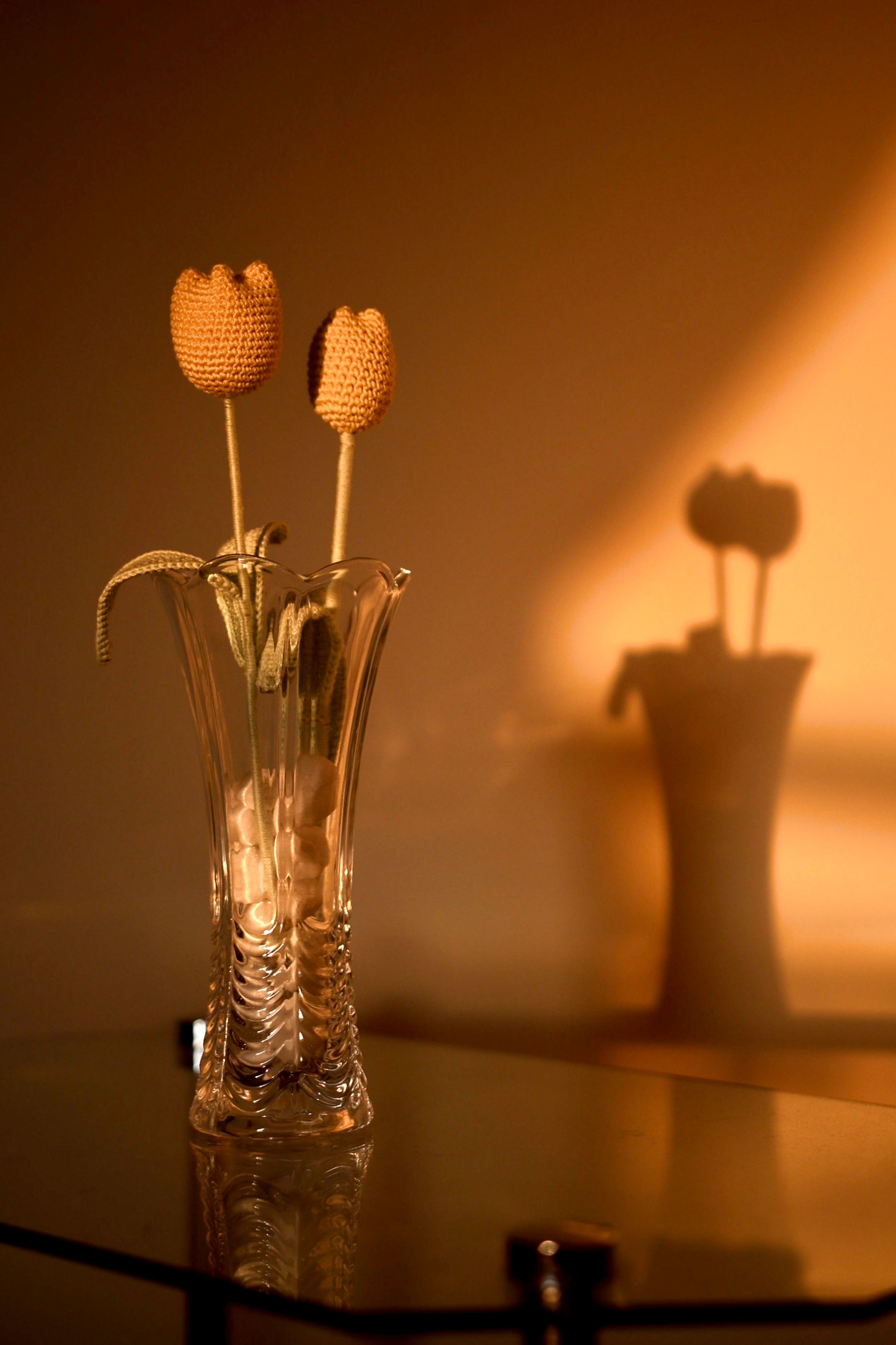 A small arrangement of handmade crochet flowers in a glass vase
